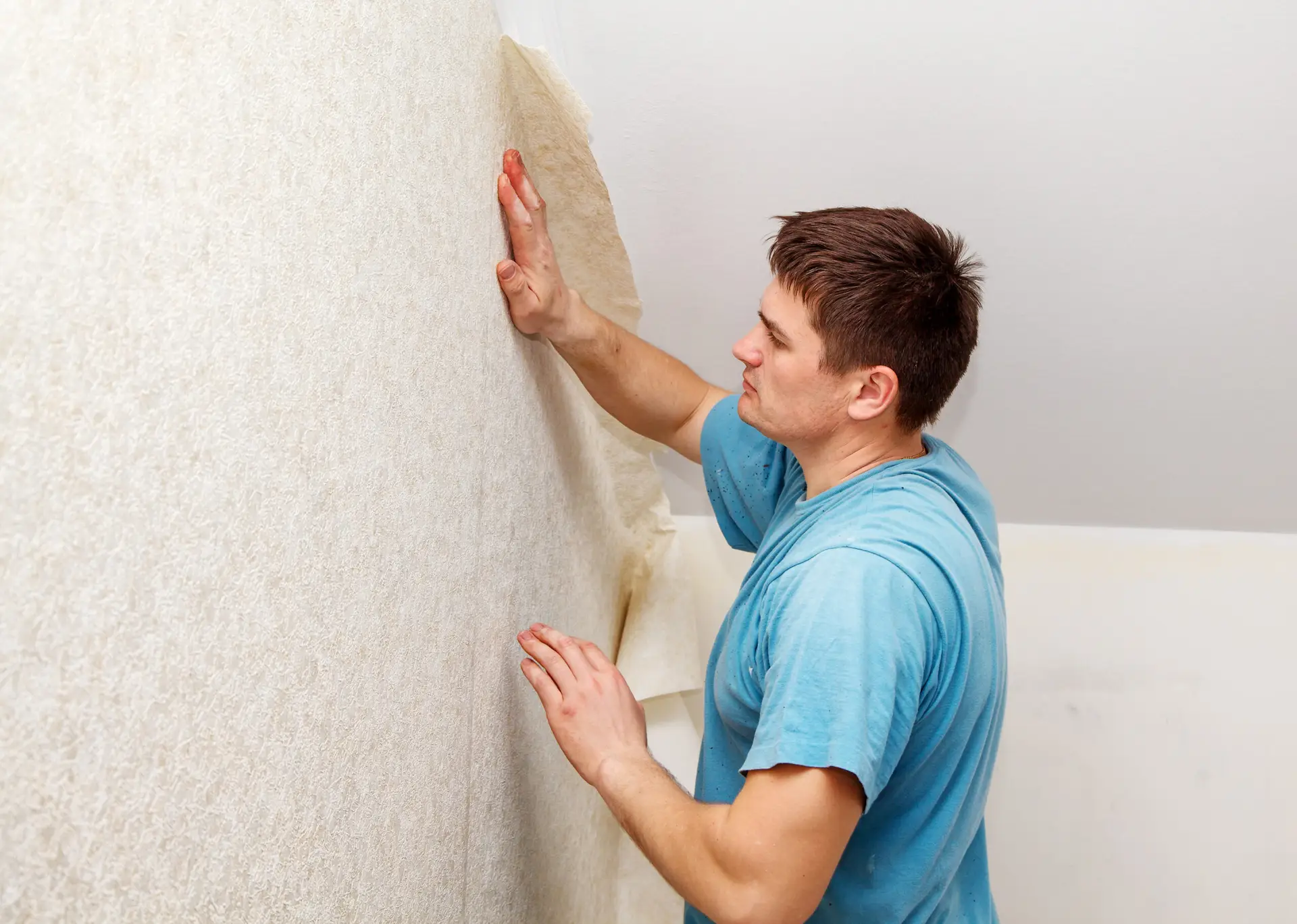 young worker smoothing wallpaper in his house closeup